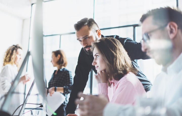 Mann und Frau schauen im Büro lächelnd gemeinsam auf Monitor